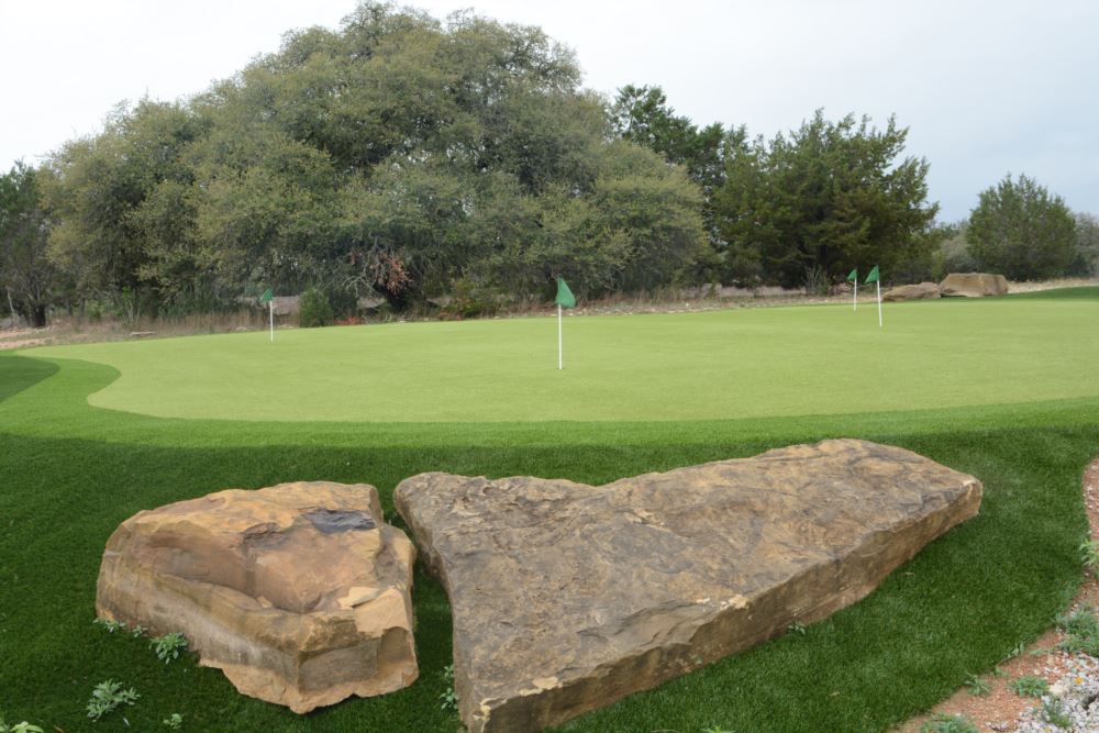 artificial turf used in a putting green with a rock in the forefront