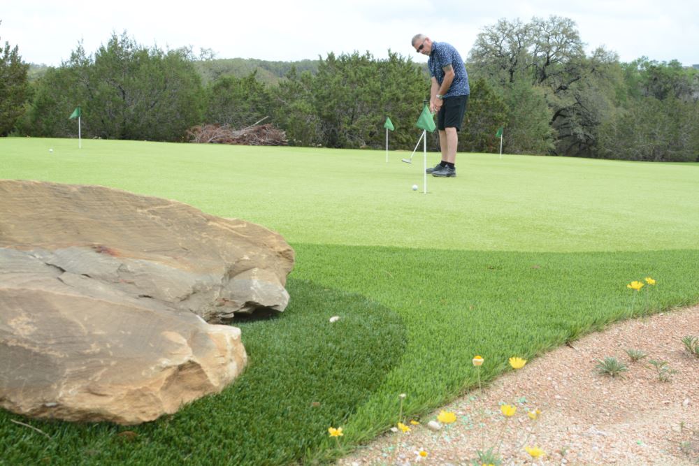 Artificial turf putting green being used by a man with a putter
